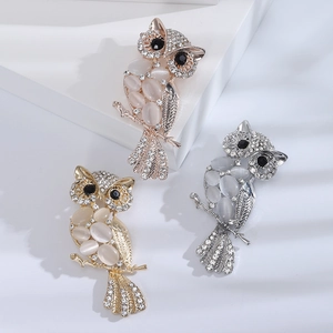 Fashionable owl brooches set with cat eye stones and rhinestones in three metallic finishes