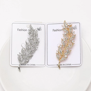 Détails macro des broches en feuilles dorées et argentées avec strass scintillants