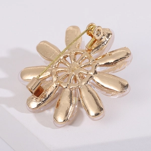 Macro view of gold metal flower brooch back with safety pin clasp on white stone