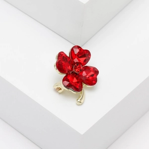 Detail of red heart-shaped crystals forming a golden four-leaf clover brooch on white steps