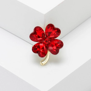Close-up of heart-shaped red crystal clover brooch with golden metal setting