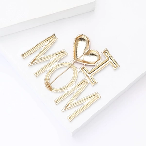Macro detail showing the back safety pin mechanism of a gold alloy I Love Mom brooch