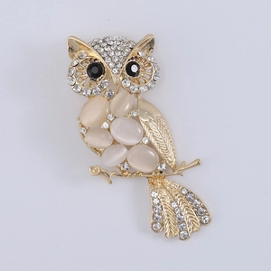 Macro detail of owl brooch featuring cat eye stones and sparkling crystals on golden alloy