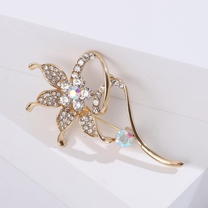 Macro detail of gold flower brooch featuring sparkling white rhinestones and elegant curves