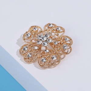 Detailed close-up of golden hollowed flower brooch with sparkling white zircons