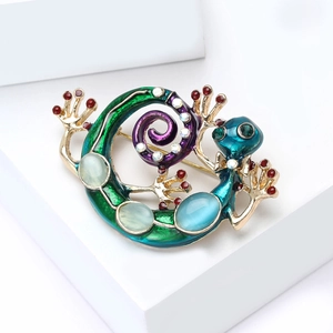 Detailed close-up of a golden lizard brooch with emerald enamel and cat's eye stones