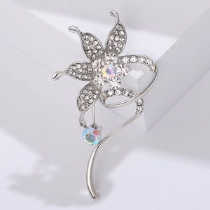 Macro shot of a silver flower brooch with sparkling AB rhinestones and curved metal detail