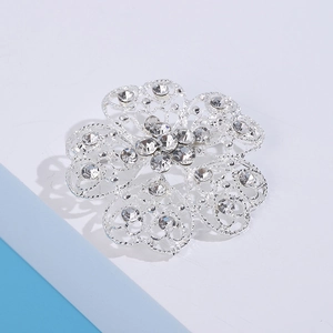 Close-up of silver flower brooch with filigree hollow petals and sparkling rhinestones