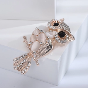 Detail of rose gold owl brooch with white cat eye stone and sparkling rhinestones
