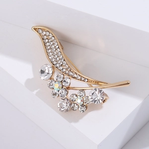 Detail view of crystal leaf and flower brooch on a white geometric display stand
