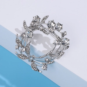 Detail van zilveren kransbroche met fonkelende kristallen op een geometrische standaard