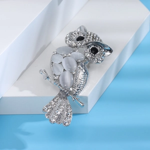 Macro shot of owl brooch with white opal belly and sparkling crystal pavé details