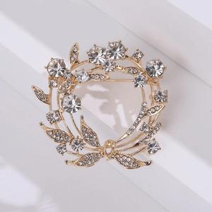 Detail van een gouden olijfkrans broche met fonkelende strassteentjes en bladontwerp