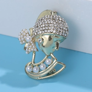 Detailed close-up of a vintage golden lady brooch with sparkling rhinestones and white pearls