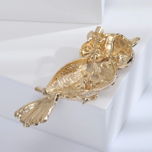 Close-up of golden owl brooch back view showing pin clasp and hollow metal texture