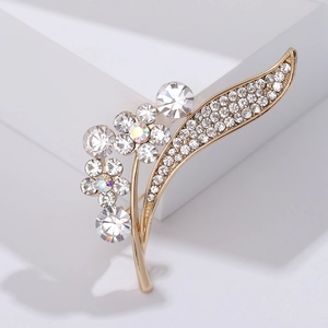 Close-up of elegant gold flower brooch with sparkling rhinestones on white display