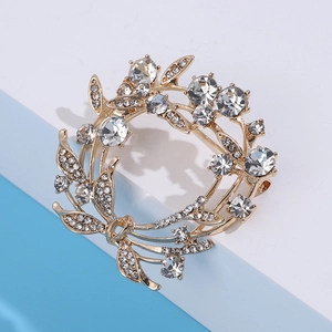 Detail van een kristallen olijfkrans broche met goudkleurig metaal en fonkelende steentjes