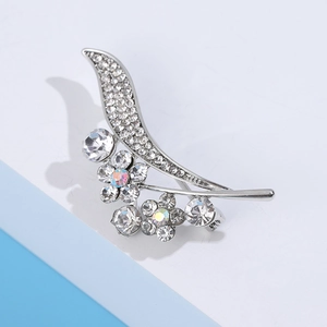 Macro shot of silver floral brooch with aurora rhinestones and curved pave leaf design