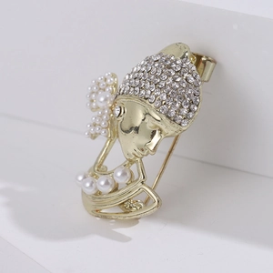 Detail of artistic gold portrait brooch featuring sparkling rhinestones and elegant pearls