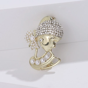 Vintage gold brooch featuring a girl with pearl earring and rhinestone hat detail