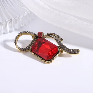 Detail of red crystal brooch with vintage gold ribbon and grey rhinestones on silk