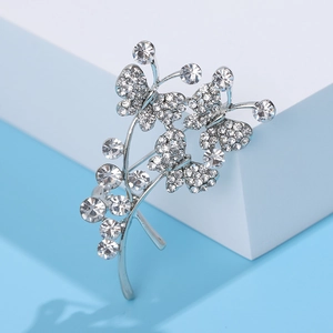 Broche bouquet de papillons argentés avec strass clairs sur fond bleu et blanc moderne