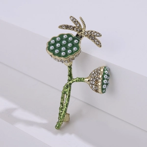 Detailed close-up of golden dragonfly lotus brooch with green enamel and pearls