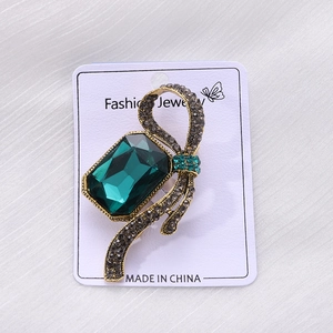 Detailed macro view of an emerald-style brooch with green crystal and vintage gold setting