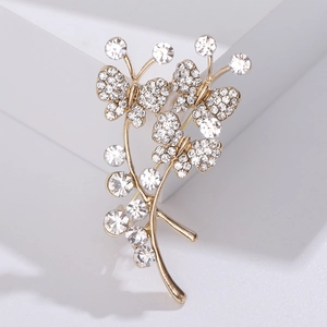 Gros plan d'une broche bouquet papillon dorée avec cristaux sur pierre blanche