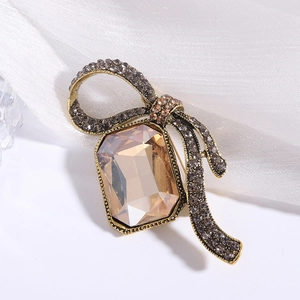 Elegant vintage bow brooch with champagne crystal and grey rhinestones on white fabric