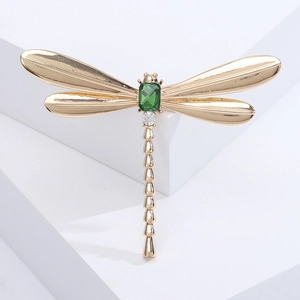 Detailed close-up of golden dragonfly brooch with green gemstone and sparkling crystals
