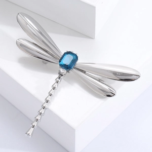 Detailed macro view of dragonfly brooch with silver wings and blue rectangular gemstone