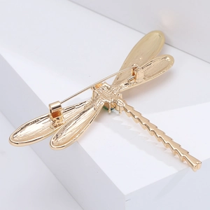 Detailed back view of golden dragonfly brooch showing safety pin and green gemstone