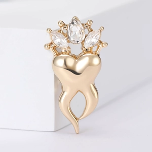 Elegant gold crown heart brooch with sparkling rhinestones on a white pedestal