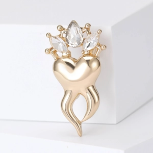 Detailed macro of golden crown brooch with sparkling heart shape and inlaid gemstones