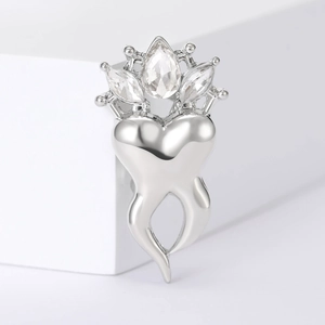 Detailed macro view of a silver crown-shaped tooth brooch with sparkling crystal rhinestones