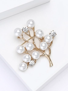 Détail macro d'une broche arbre dorée élégante avec perles blanches et strass brillants