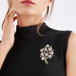 Élégante broche bouquet en or avec strass scintillants fixée sur un pull noir