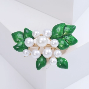 Detail shot of lily of the valley brooch with white pearls and green enamel on a pedestal