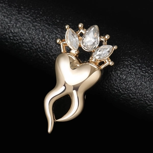 Macro shot of gold-plated crown tooth brooch with sparkling cubic zirconia crystals