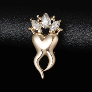 Macro shot of gold crown tooth brooch with sparkling rhinestones on black leather