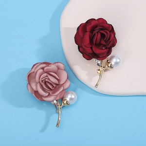 Close-up of burgundy and pink camellia fabric brooches with pearls and rhinestones