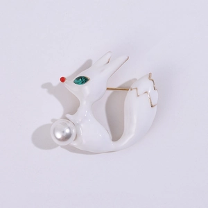 Gros plan détaillé d'une broche renard blanc avec yeux verts et perle élégante