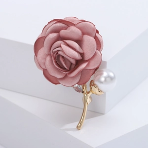 Detailed macro view of pink fabric rose brooch with white pearl and sparkling rhinestones