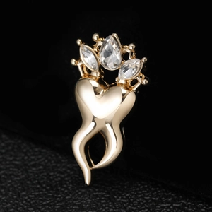 Macro shot of gold-plated crown tooth brooch with sparkling rhinestones on black leather