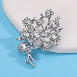 Vue détaillée de la broche fleur argentée avec strass scintillants sur fond bleu ciel