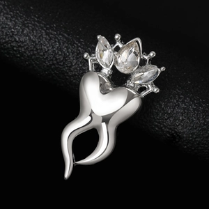 Macro shot of silver tooth brooch with crown detail and sparkling crystal stones