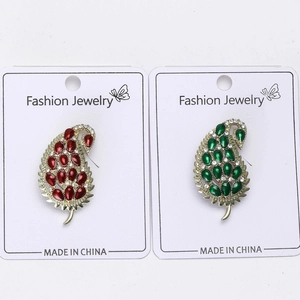 Detail showing leaf-shaped brooches with wine red and emerald gemstones in gold setting