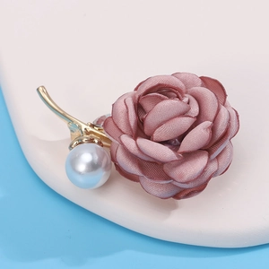 Detailed macro view of an elegant dusty pink fabric camellia brooch with pearls and rhinestones