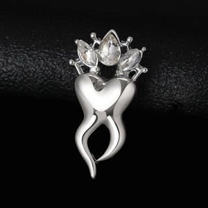 Macro shot of silver tooth brooch with crown design and sparkling gemstones on leather